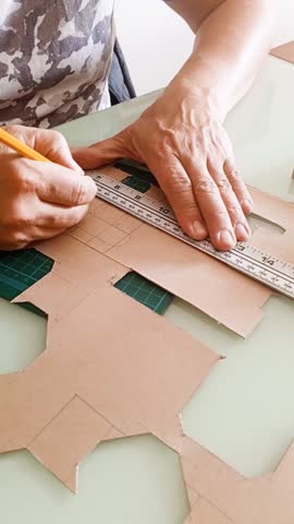 An unrecognizable man drawing the layout of a cardboard box, packaging prototyping, homemade industrial design, and crafts