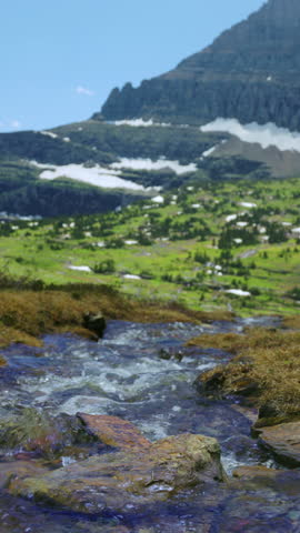 Glacier National Park in Montana features stunning landscapes of majestic mountains, flowing streams, and vibrant greenery, capturing the essence of natures beauty and splendor in every season