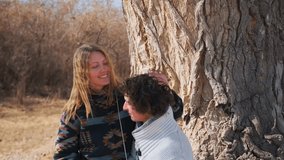 A young couple enjoys a romantic date in a spring park. The woman, with loose golden hair and a warm smile, sits on the man lap, gently stroking his curls and leaning in to kiss his head. - Powered by Shutterstock - Get 15% off with code: PIKWIZARD15
