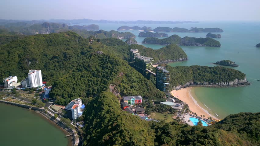 Drone aerial view of Cat Ba Island in Vietnam, showing tropical coastline, sandy beach and green hills overlooking the sea. Scenic landscape of Ha Long Bay archipelago.