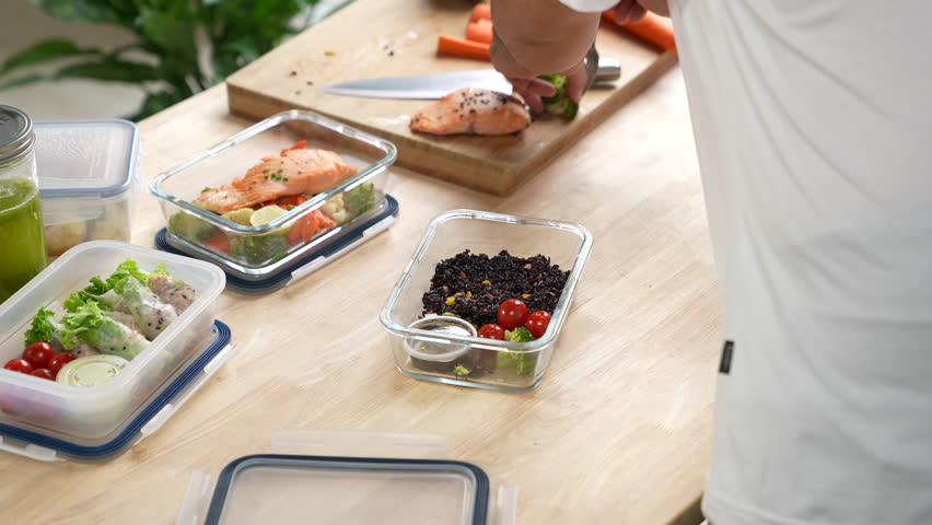 Man preparing healthy homemade meal prep in food container with fresh food at home.