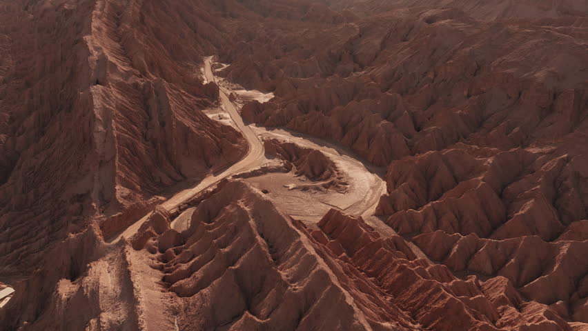 Aerial view of Mars Valley in the Atacama Desert during a stunning summer sunset with warm colors over dramatic rock formations and a surreal Martian landscape