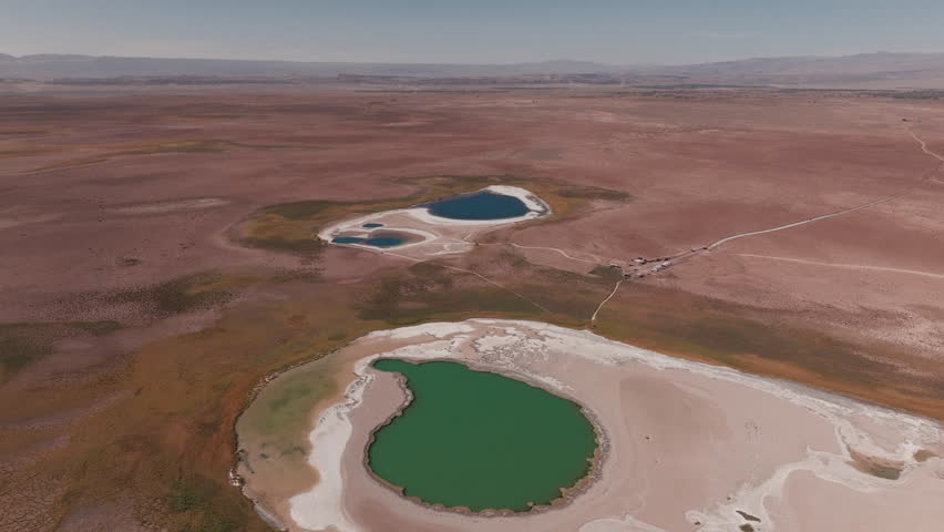 Aerial view of stunning lagoons in the Atacama Desert surrounded by volcanic mountains and salt flats in the high Andean plateau of northern Chile during a sunny summer day