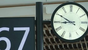 A time lapse shows the hands of a classic analog clock moving quickly in an airport or train station, next to a digital gate sign. - Powered by Shutterstock - Get 15% off with code: PIKWIZARD15