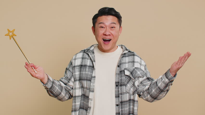 Magician witch Asian middle-aged man gesturing with magic wand fairy stick, making wish come true, casting magician spell, advertising holidays sale discount. Mature Chinese guy on beige background