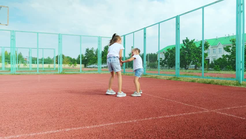 Sports Education. Full body length in action of children, little girl sisters playing basketball on a court, spending time outdoors