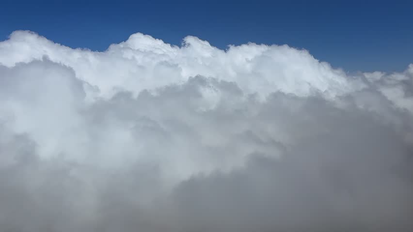 An immersive pilot’s view from a jet cockpit piercing storm clouds under a deep blue sky. Aerial footage taken from a jet cockpit. Ultra-realistic 4K shot.