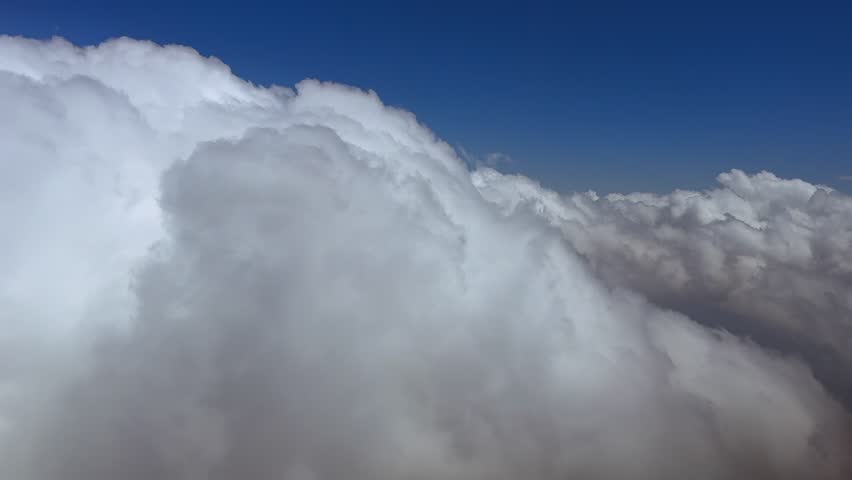 Immersive pilot’s perspective flying through white storm clouds in a deep blue sky. ultra-realistic 4K shot.