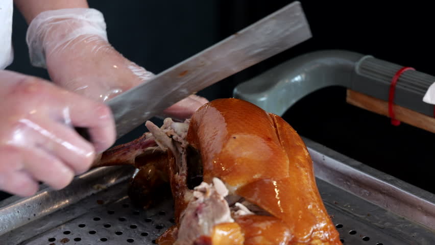 Chinese food: chef slicing meat of Beijing roast duck in restaurant.	