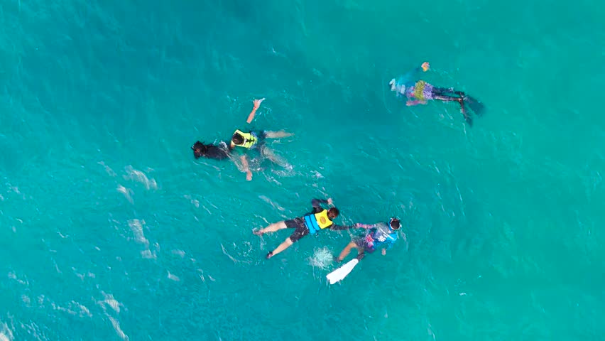 Aerial view of a group of adults snorkeling and swimming in the turquoise ocean water, Boracay, Philippines.