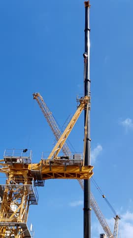 Tower crane or mobile crane erected beside under construction building.
Yellow color Tower crane used for lifting heavy items from ground to top level. Building Cranes for under construction building