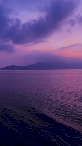 Purple sunset sky over tropical sea and mountains
