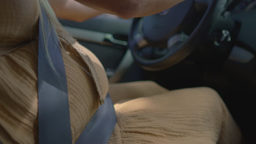 Close-up of large pregnant belly while woman drives a car. Symbol of independence, mobility, and confidence during maternity. Active motherhood and daily life during pregnancy concept.