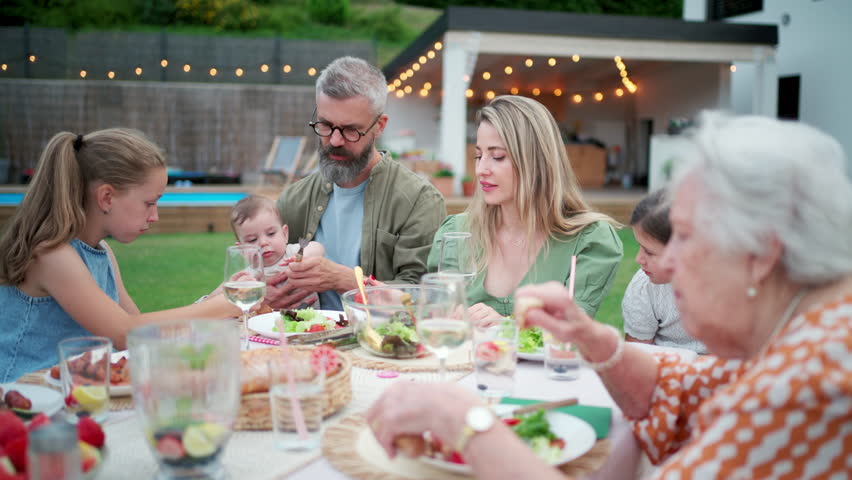 Multigenerational family enjoying summer barbecue in backyard.