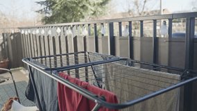 Person dries freshly washed clothes on black drying rack outdoors. Concept of eco friendly lifestyle and home routine - Powered by Shutterstock - Get 15% off with code: PIKWIZARD15