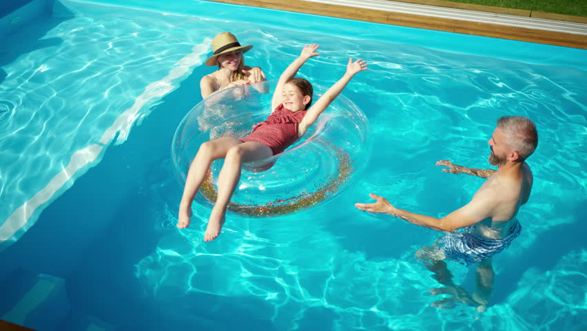Parents playing with daughter in pool.