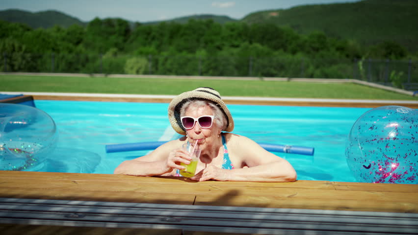 Happy senior woman relaxing in pool on summer day.