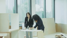 Two female architects reviewing blueprint at office desk, concept of teamwork, construction planning, professional design and collaboration in workplace - Powered by Shutterstock - Get 15% off with code: PIKWIZARD15