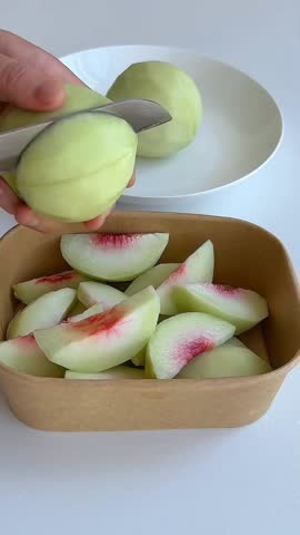 Hands carefully cutting juicy peaches into slices.