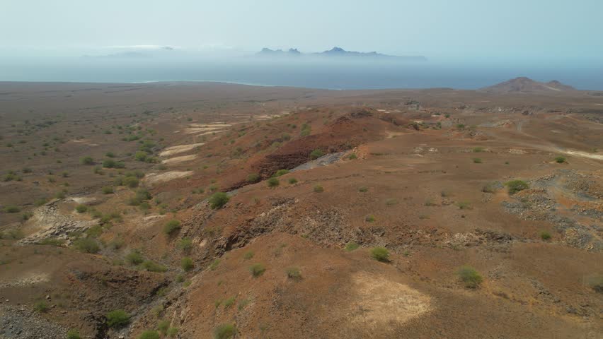 CAPE VERDE - 8.20.2025 - Stunning aerial footage passing over dry landscapes of Santo Antao Island with a view of Sao Vicente in the misty distance.
