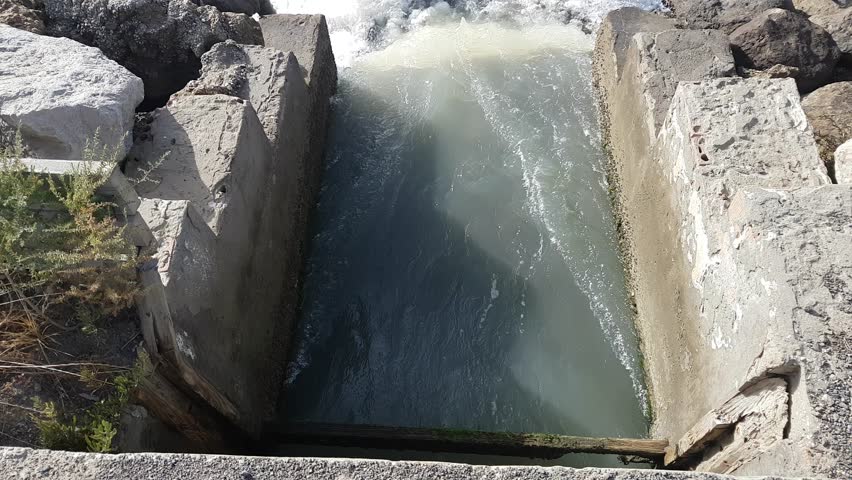 Torrents of water rush through floodgates in the Carboneros marshes, Chiclana de la Frontera, Cádiz, Spain. A dynamic scene of nature, flow, and hydraulic infrastructure.