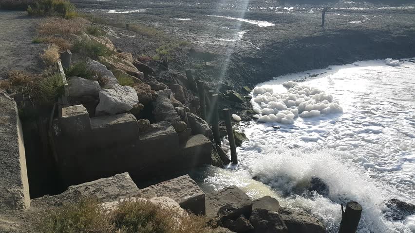 Torrents of water rush through floodgates in the Carboneros marshes, Chiclana de la Frontera, Cádiz, Spain. A dynamic scene of nature, flow, and hydraulic infrastructure.