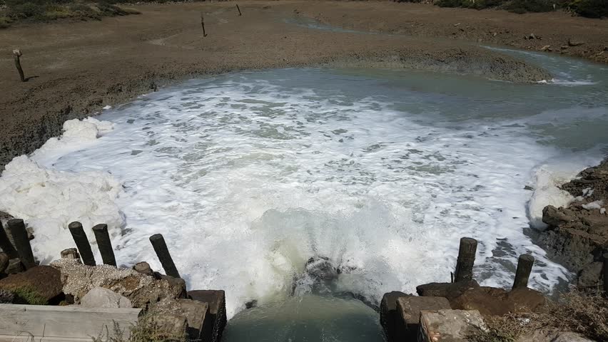 Torrents of water rush through floodgates in the Carboneros marshes, Chiclana de la Frontera, Cádiz, Spain. A dynamic scene of nature, flow, and hydraulic infrastructure.