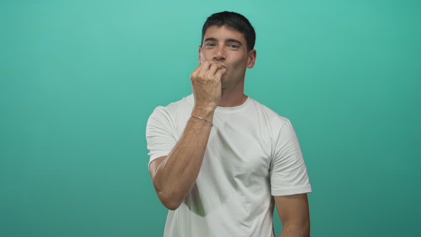 Man blows a kiss from his lips against a green studio backdrop; affection admiration flirtation sentiment.