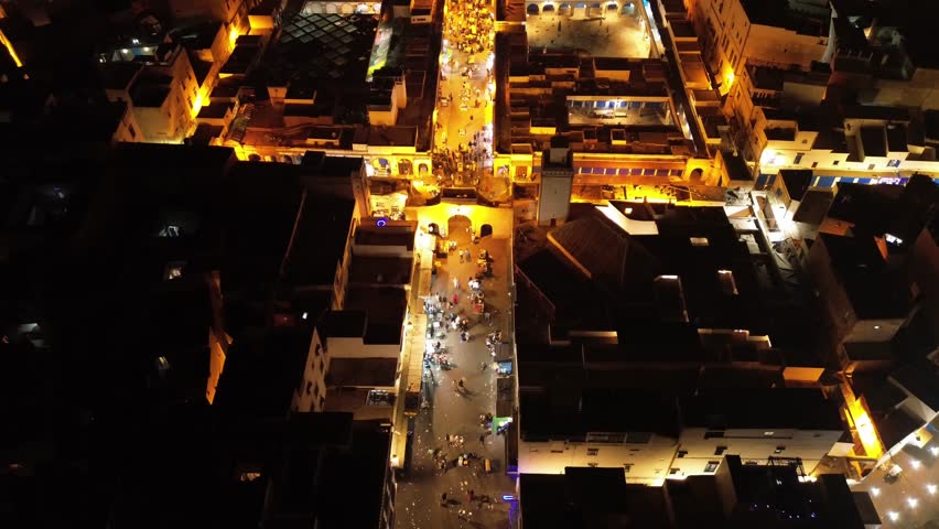 Spectacular aerial view of the city of Essaouira at night, filmed by drone. The lights of the medina, the port, and the ocean create a unique, magical atmosphere.