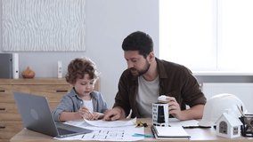 Choice of profession. Father and his son exploring engineering drawings at table indoors, camera moving in - Powered by Shutterstock - Get 15% off with code: PIKWIZARD15