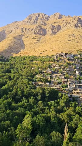 Kamalla stepped village in summer, built along a rocky hillside with tiered stone houses and contrasting greenery below, reflecting traditional adaptation to mountainous terrain.  
