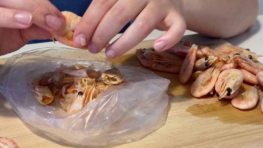 Peeling boiled shrimp on a wooden cutting board at home