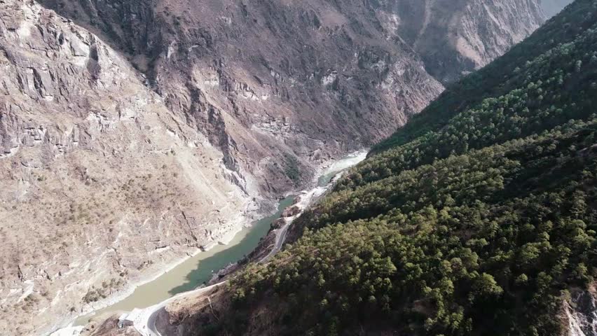 Aerial view of the Jinsha River flowing through a valley surrounded by mountains and lush forest in the Tiger Leaping Gorge, Yunnan, China