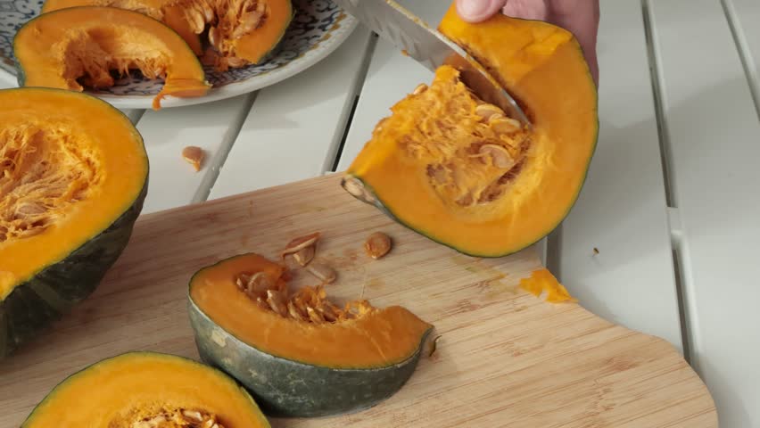 Anonymous cut pumpkin on wooden board. Farm products and healthy eating. Seasonal food, vegetarian dish.