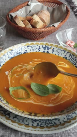 Anonymous eat pumpkin soup with cream in blue patterned porcelain plate. Homemade healthy food and serving. Farm products.