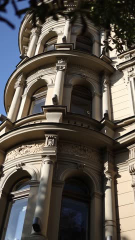 Vertical screen historic building with ornate classical architecture and decorative columns illuminated by warm sunlight showing details of arched windows and elegant stonework