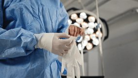 A medical professional putting on surgical gloves in an operating room, preparing for a procedure. A doctor, wearing a mask and surgical gown, stands in an operating room, preparing for a procedure. - Powered by Shutterstock - Get 15% off with code: PIKWIZARD15