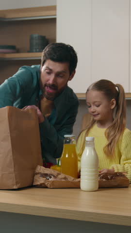 Happy Caucasian family at kitchen home unpacking bag shopping purchase natural product customers clients enjoying quality eco good delivery father give orange fruit to little daughter child kid girl