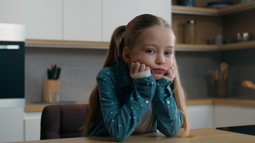 Portrait upset frown little offended Caucasian child girl kid at kitchen say no answer not shaking head looking at camera negative disagree family misunderstanding daughter unhappy displeased at home