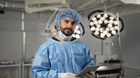A doctor wearing a surgical gown and cap consults a tablet in a modern operating room, preparing for surgery. A doctor or surgeon, wearing a mask and surgical gown - Powered by Shutterstock - Get 15% off with code: PIKWIZARD15