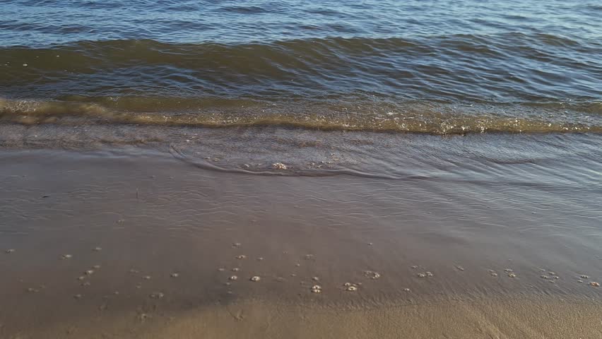 Close-up of gentle ocean waves lapping against the sandy beach in Yyteri, Finland. Relaxing coastal scenery with natural water movement.