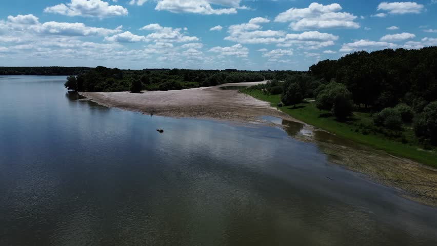 Aerial view of Danube River meandering through forested landscape and sandbanks near Belegis, Serbia. A long coastline with sand along the river. Horizontal 4k footage