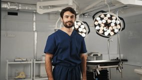 A smiling surgeon with crossed arms stands in an operating room, looking directly at the camera. A male doctor, possibly of Mediterranean descent, prepares for surgery in a modern operating room - Powered by Shutterstock - Get 15% off with code: PIKWIZARD15