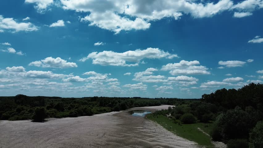 Aerial view of Danube River meandering through forested landscape and sandbanks near Belegis, Serbia. A long coastline with sand along the river. Horizontal 4k footage