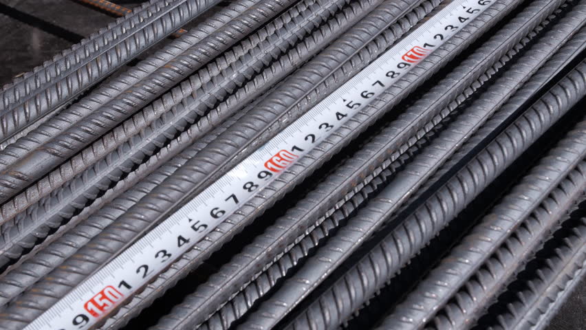 Measuring steel reinforcement bars with tape measure at construction site