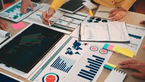 Diverse team members engage in data analysis and discussion, utilizing charts and graphs on a modern workspace to formulate strategic plans and drive insights. SACTR - Powered by Shutterstock - Get 15% off with code: PIKWIZARD15