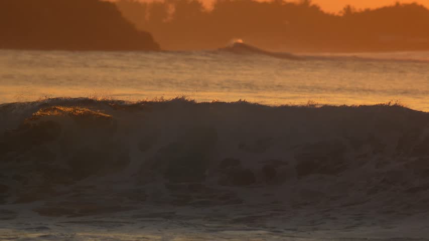 Male surfer sit on his surfboard in Indian Ocean at sunset time. Powerful wave crashing behind his body.Maldives