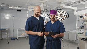 Two male surgeons of African and European descent review a tablet together in an operating room, discussing patient data. Two surgeons of diverse ethnicity engage - Powered by Shutterstock - Get 15% off with code: PIKWIZARD15