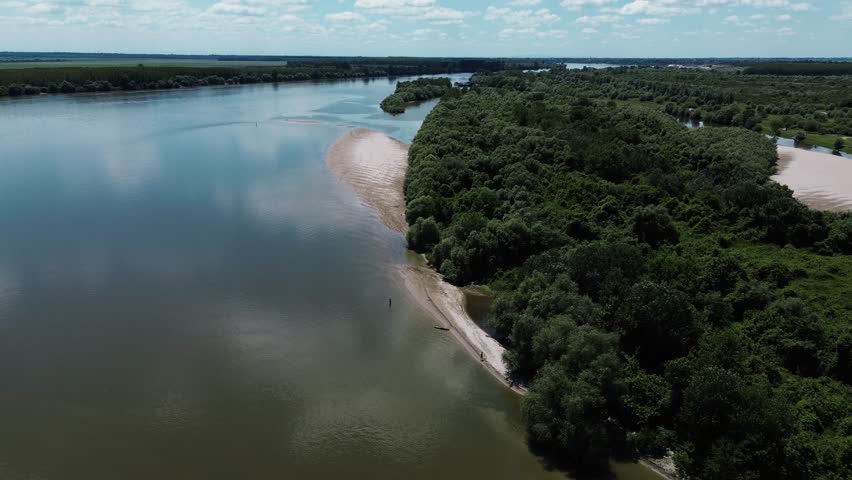 Aerial view of Danube River meandering through forested landscape and sandbanks near Belegis, Serbia. A long coastline with sand along the river. Horizontal 4k footage