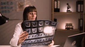 Mature female Doctor looking on x-ray image or ct scan at night duty - Powered by Shutterstock - Get 15% off with code: PIKWIZARD15